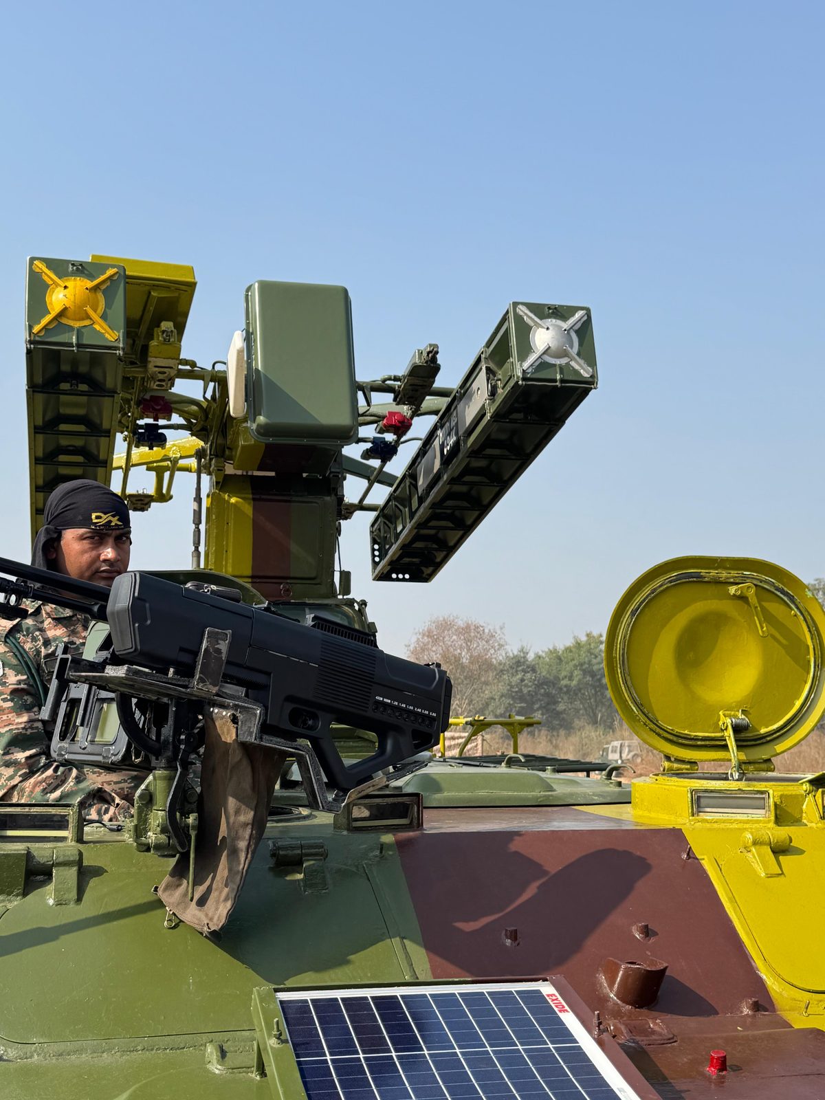 Soldier operating a vehicle-mounted anti-drone jammer and radar system atop an armoured vehicle