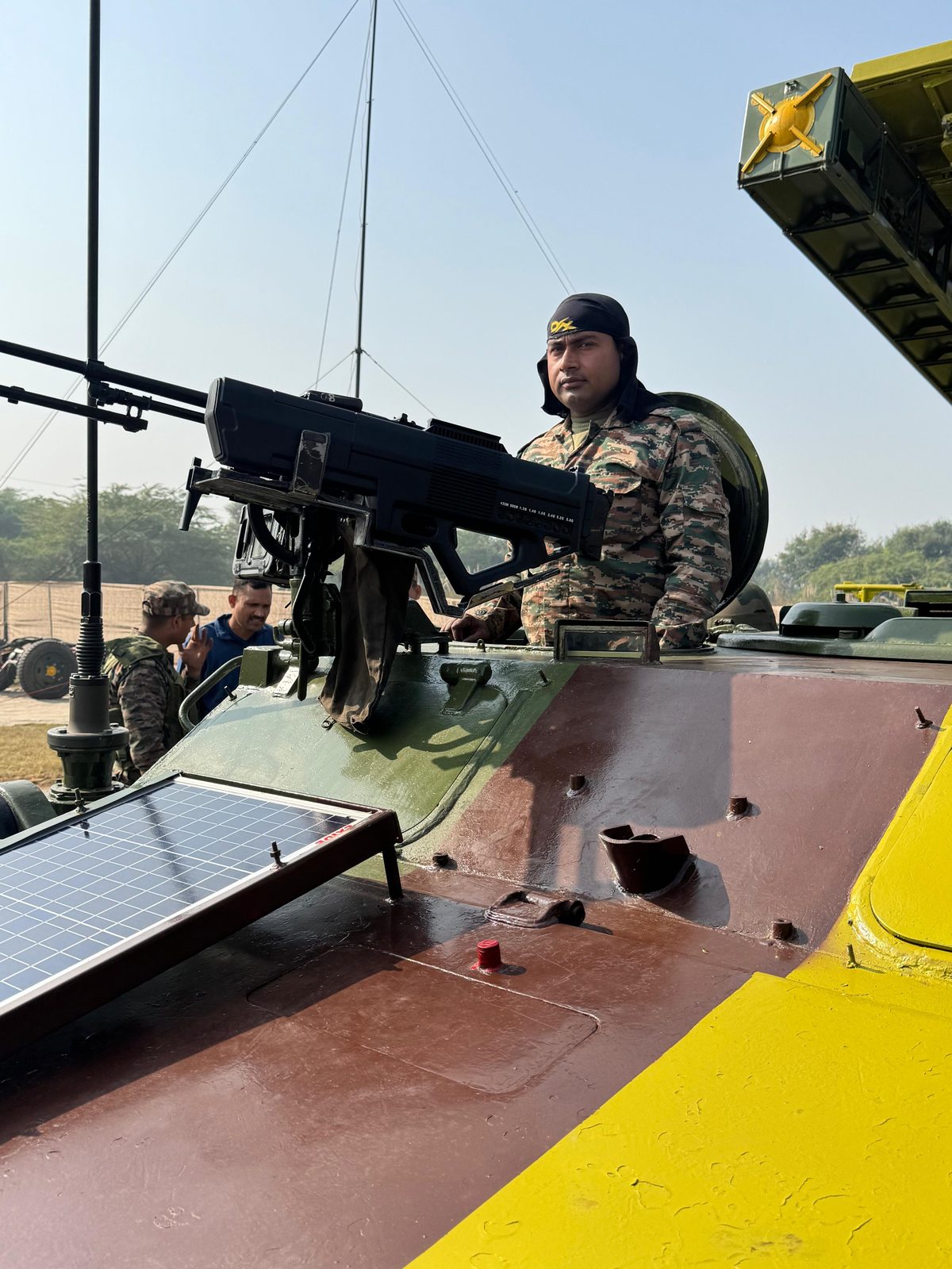 Soldier holding an anti-drone jamming weapon aboard an armoured vehicle with radar and solar panel