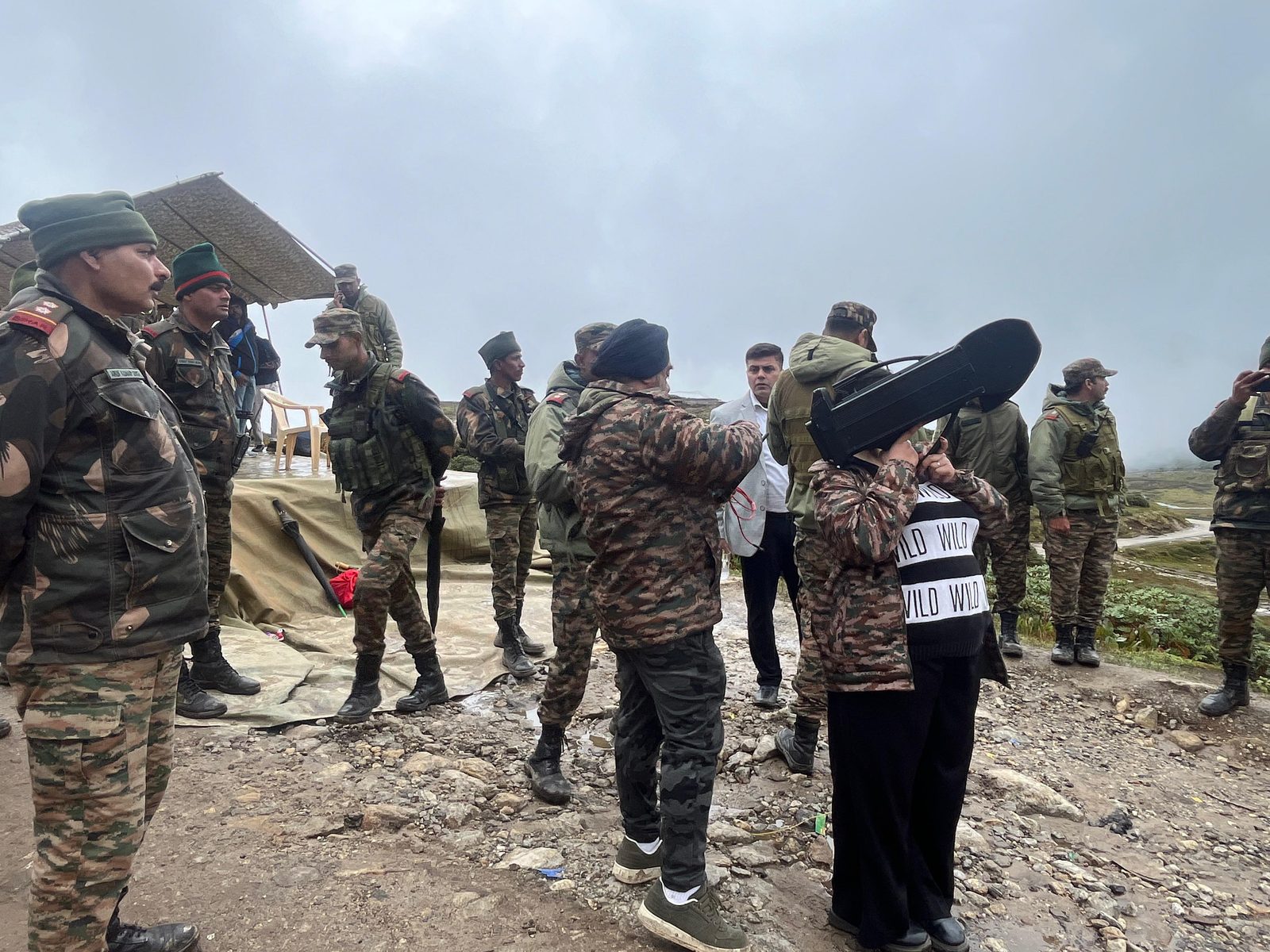 Soldiers and personnel gathered around a handheld anti-drone jammer at a high-altitude outpost