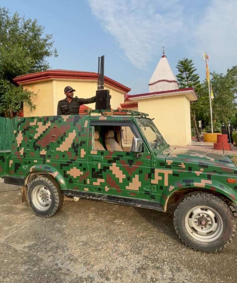 Soldier operating a vehicle-mounted anti-drone antenna array on a camouflaged military jeep