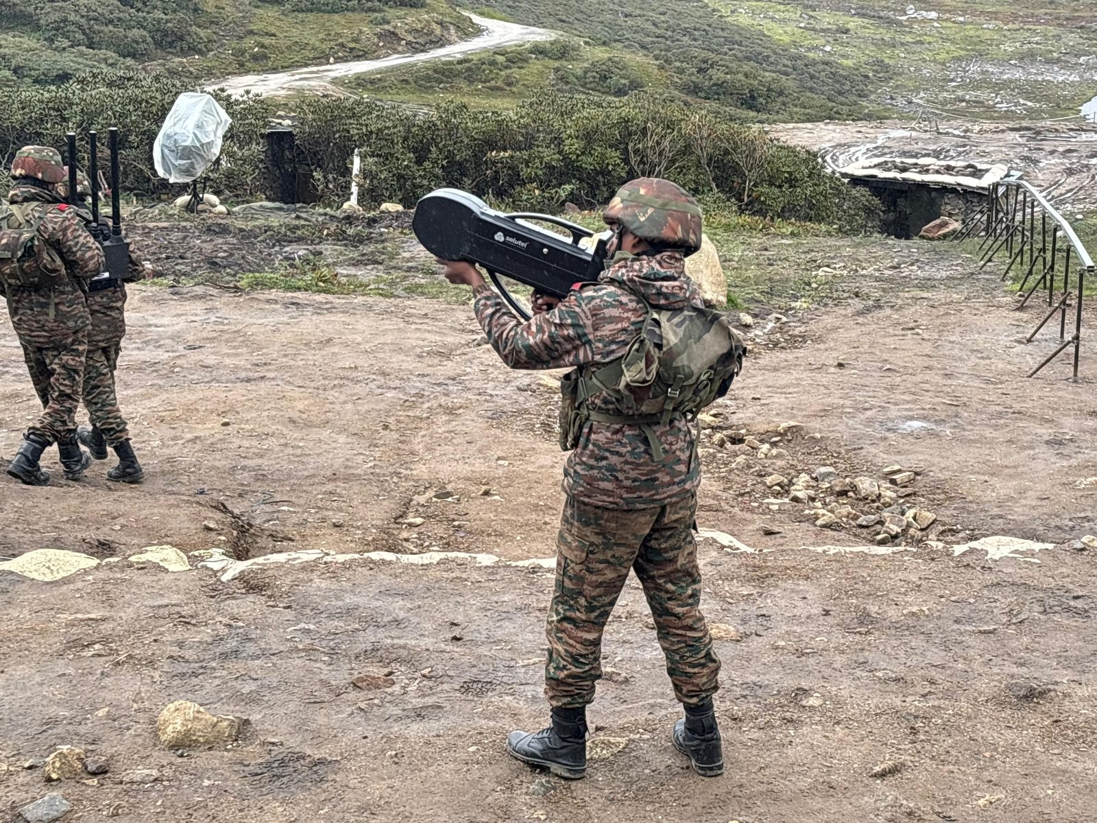 Soldier aiming a Black Wave Defence handheld anti-drone jammer skyward on hilly terrain